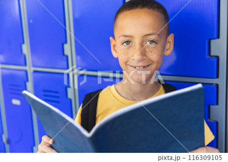 Biracial boy smiles holding a book in school 116309105