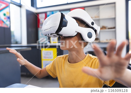 A young biracial student explores virtual reality using a headset in the classroom 116309128