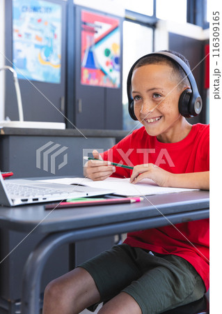 Biracial boy studies at school using a laptop, with copy space Biracial boy studies at school using a laptop, with copy space 116309165