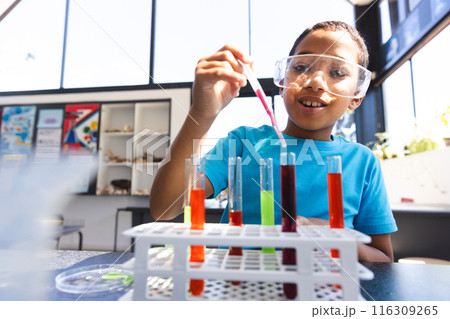 Biracial boy conducts an experiment in a science classroom at school 116309265