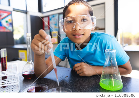 Biracial boy engages in a science experiment at school in the classroom 116309306