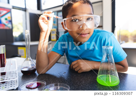 Biracial boy engages in a science experiment at school in the classroom 116309307