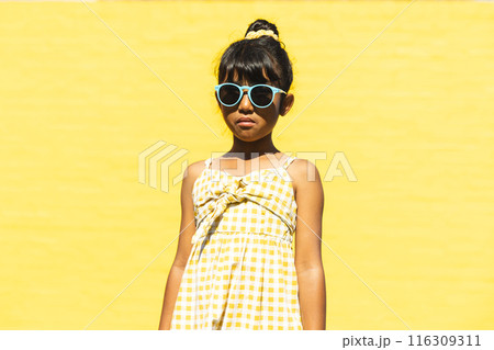 Biracial girl wearing sunglasses and a sundress poses confidently outdoors Biracial girl wearing sunglasses and a sundress poses confidently outdoors 116309311