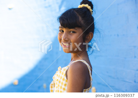 Biracial girl smiles brightly against a blue background Biracial girl smiles brightly against a blue background 116309337