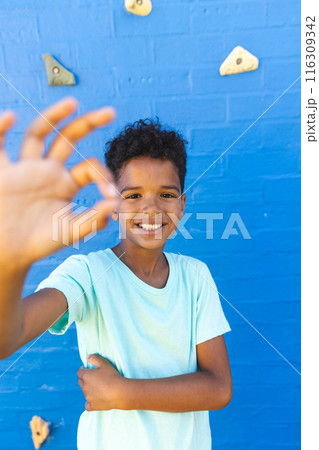 Biracial boy smiles in front of a climbing wall 116309342