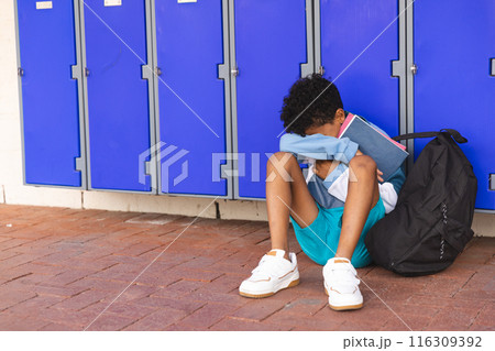 Biracial boy sits alone at school, with copy space 116309392