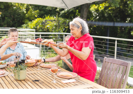 Diverse senior female friends sharing meal outdoors 116309453
