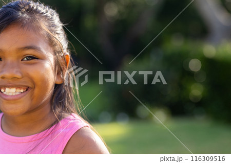 Outdoors, young biracial girl smiling brightly, wearing a pink top, copy space Outdoors, young biracial girl smiling brightly, wearing a pink top, copy space 116309516