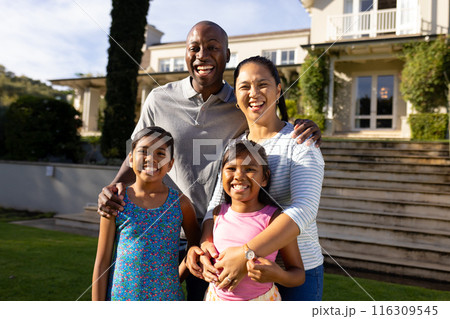 Outdoors, happy biracial family of four smiling together outside their home Outdoors, happy biracial family of four smiling together outside their home 116309545
