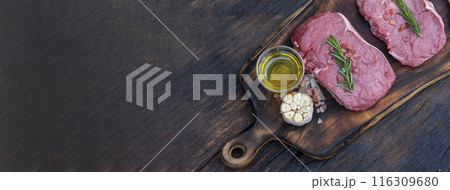 Banner Raw meat beef steak organic fresh ingredient on wooden board table background in kitchen with rosemary, salt, garlic, tomato, olive oil. Meat beef on wooden plate for beefsteak with copy space 116309680