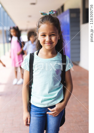 Biracial girl smiling with backpack, standing in front of school lockers Biracial girl smiling with backpack, standing in front of school lockers 116309756