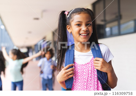 Biracial girl with backpack smiling at school 116309758