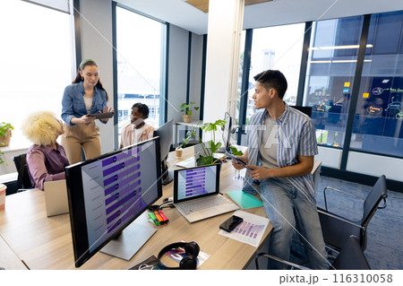 Diverse colleagues collaborate in modern office business; one shows a tablet, copy space Diverse colleagues collaborate in modern office business; one shows a tablet, copy space 116310058