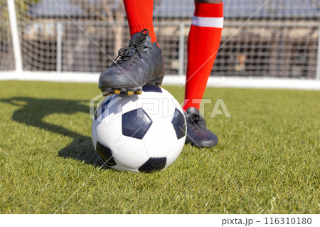 African American athlete training with soccer ball on a field 116310180
