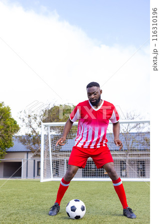 African american male athlete training with a soccer ball on the field, copy space 116310196