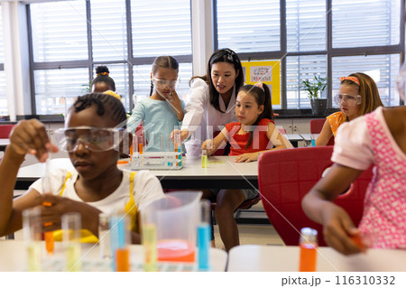Diverse female teacher and schoolgirls with chemistry items and liquids in elementary school class Diverse female teacher and schoolgirls with chemistry items and liquids in elementary school class 116310332