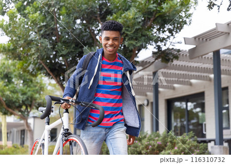 undefined walking with bicycle, smiling and enjoying outdoor campus environment 116310732
