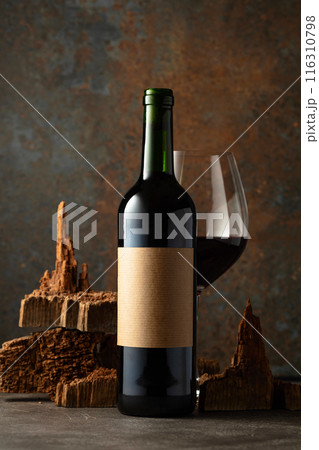 Glass and bottle of red wine with pieces of old wood on a rusty background. 116310798