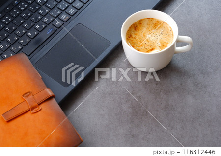 淹れたてのコーヒーを飲みながら、ノートパソコンとシステム手帳で、デスクワークをしているイメージ 淹れたてのコーヒーを飲みながら、ノートパソコンとシステム手帳で、デスクワークをしているイメージ 116312446