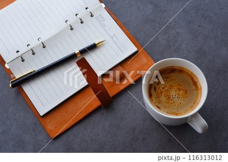 ミルクをたっぷり入れたコーヒー、カフェ・ラッテを飲みながら、日記をつけているイメージ ミルクをたっぷり入れたコーヒー、カフェ・ラッテを飲みながら、日記をつけているイメージ 116313012