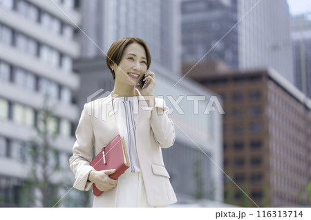赤い手帳を持ってスマホで会話するビジネスウーマン 116313714