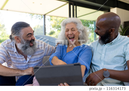 At home, Diverse group of friends laughing and watching something on tablet together 116314173