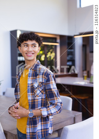 Smiling teenage boy in casual outfit standing in modern home kitchen Smiling teenage boy in casual outfit standing in modern home kitchen 116314823