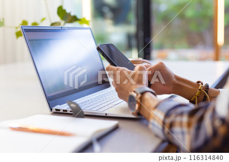 Using smartphone and laptop, teenage boy working from home office desk Using smartphone and laptop, teenage boy working from home office desk 116314840