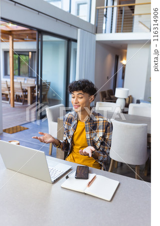 Using laptop and gesturing, teenage boy video conferencing from home office setup Using laptop and gesturing, teenage boy video conferencing from home office setup 116314906