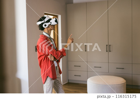 Using VR headset, young man exploring virtual environment in modern home setting Using VR headset, young man exploring virtual environment in modern home setting 116315175