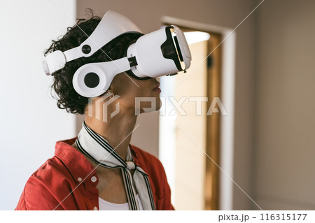 Using VR headset, young man exploring virtual reality experience at home Using VR headset, young man exploring virtual reality experience at home 116315177