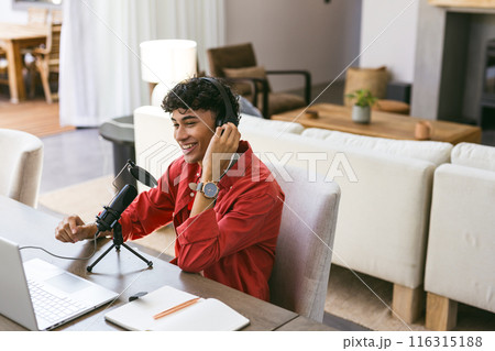 Recording podcast, young man using microphone and laptop in home office 116315188