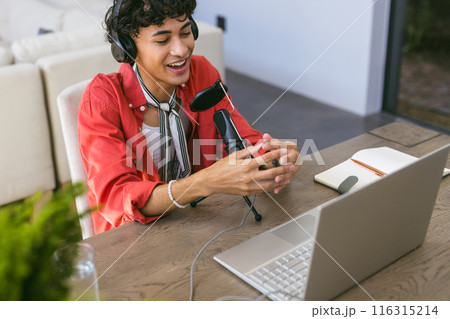 Recording podcast, young man using microphone and laptop at home office desk 116315214