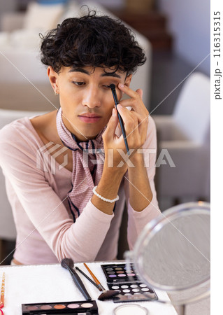 Applying eyeshadow, transgender transgender woman using makeup brush in front of mirror Applying eyeshadow, transgender transgender woman using makeup brush in front of mirror 116315315