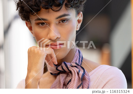 Close-up of transgender transgender woman resting chin on hand, wearing patterned scarf 116315324