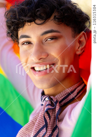 Celebrating LGBTQ+ pride, smiling transgender woman holding rainbow flag 116315384