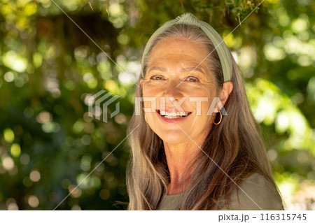 Smiling mature woman with long hair and headband enjoying outdoor nature Smiling mature woman with long hair and headband enjoying outdoor nature 116315745