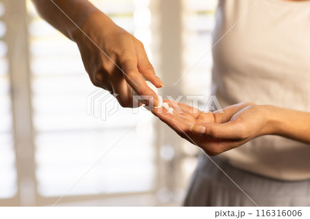Applying lotion on hands, woman focusing on skincare routine at home Applying lotion on hands, woman focusing on skincare routine at home 116316006