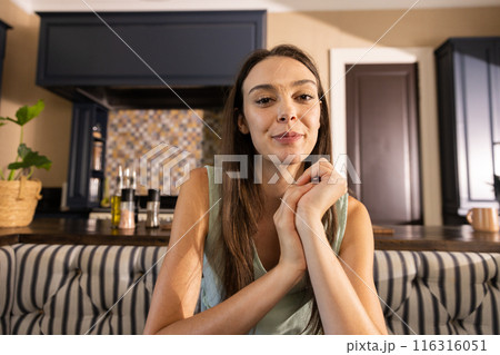 Smiling woman sitting in kitchen, looking at camera, enjoying her home 116316051
