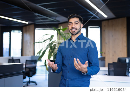 Business professional in blue shirt presenting in modern office environment 116316084