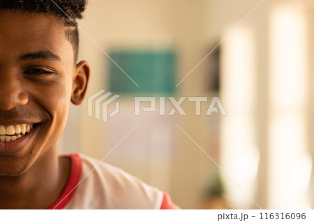 Smiling teenage boy enjoying moment in classroom at high school, copy space 116316096