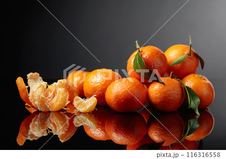 Tangerines or clementines with green leaves on a black background. 116316558