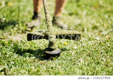 Naked legs of landowner before string weed trimmer drum. Naked legs of landowner before string weed trimmer drum. 116317408