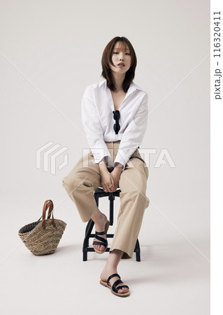 Korean Woman Poses in a Chair With Bags on the Floor 116320411