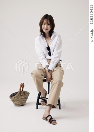 Korean Woman Poses in a Chair With Bags on the Floor Korean Woman Poses in a Chair With Bags on the Floor 116320413