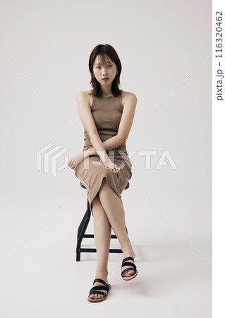 Korean Woman Sitting in Chair wearing Beige Knit Dress 116320462