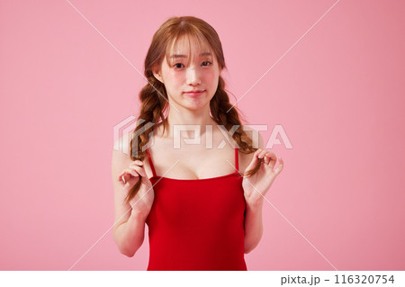A Korean woman in her 20s who wears a monokini look with a pink background and touches pigtails A Korean woman in her 20s who wears a monokini look with a pink background and touches pigtails 116320754