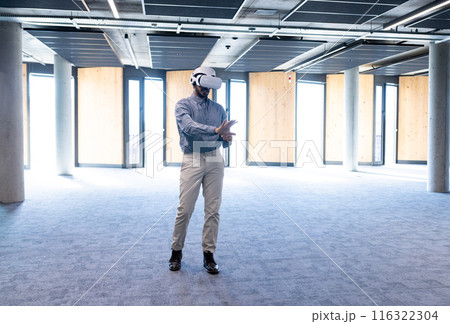 Using VR headset, man exploring virtual environment in modern office space, copy space 116322304
