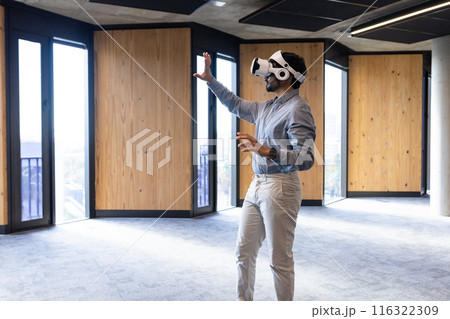 Using VR headset, man interacting with virtual environment in modern office, copy space 116322309