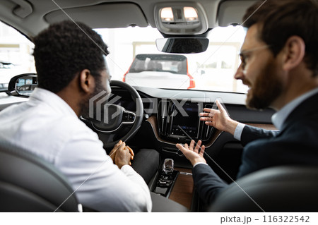 Caucasian car dealer discusses vehicle features with African American buyer Caucasian car dealer discusses vehicle features with African American buyer 116322542